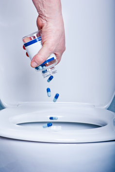 Wasting pills into toilet.