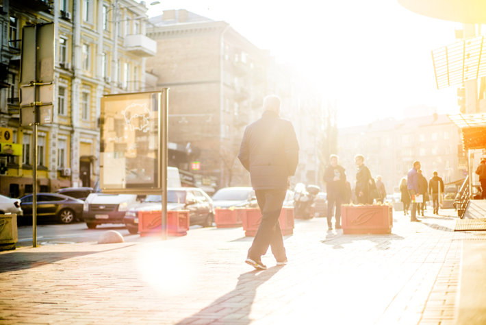 Man walking in sunshine on on a street.